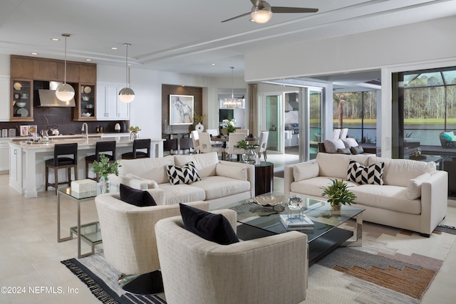 tiled living room with ceiling fan with notable chandelier