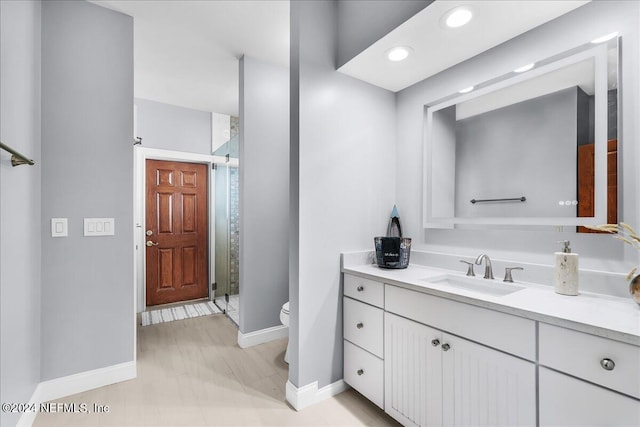 bathroom featuring toilet, vanity, and an enclosed shower