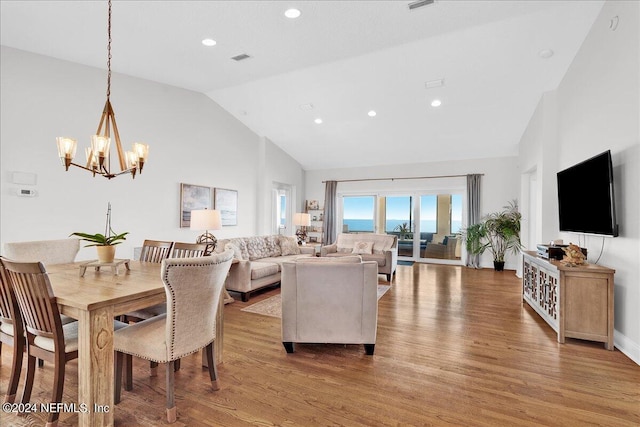 living room featuring light hardwood / wood-style floors, a notable chandelier, and vaulted ceiling