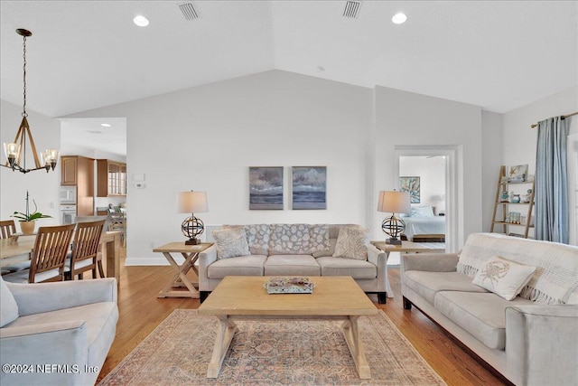 living room featuring light wood-type flooring, vaulted ceiling, and an inviting chandelier