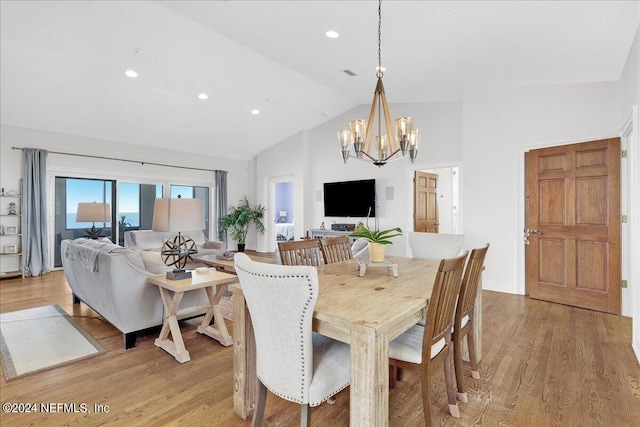 dining area with high vaulted ceiling, a chandelier, and light hardwood / wood-style flooring