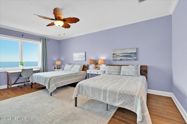 bedroom with hardwood / wood-style floors, ceiling fan, a textured ceiling, ornamental molding, and a water view