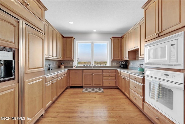 kitchen featuring backsplash, sink, white appliances, light hardwood / wood-style flooring, and light brown cabinets