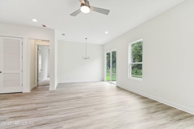 unfurnished room with light hardwood / wood-style flooring and ceiling fan with notable chandelier