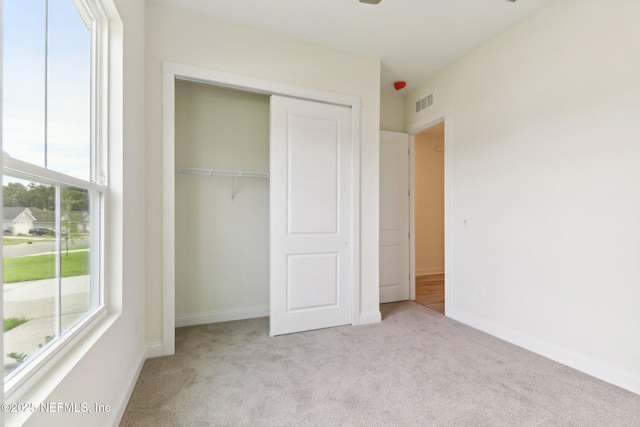 unfurnished bedroom featuring light carpet and a closet