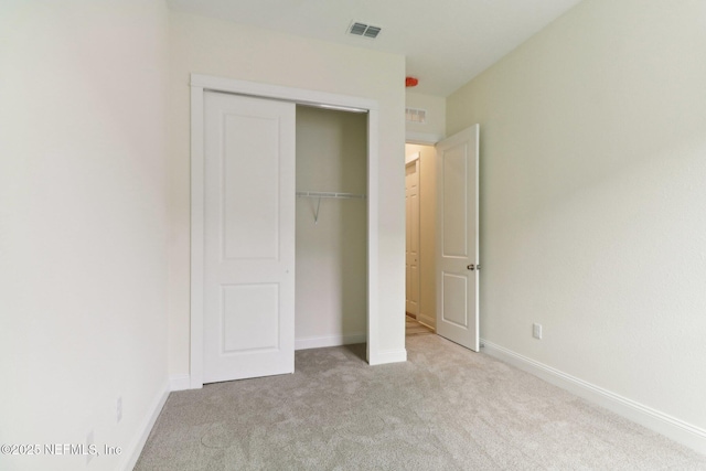 unfurnished bedroom with a closet and light colored carpet