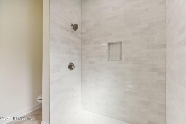 bathroom with toilet and tiled shower