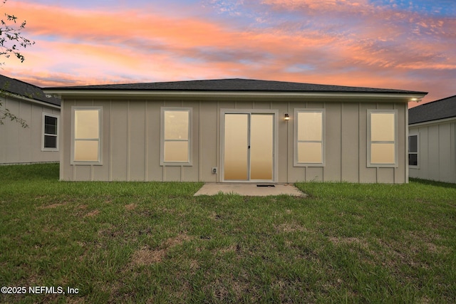 back house at dusk with a lawn