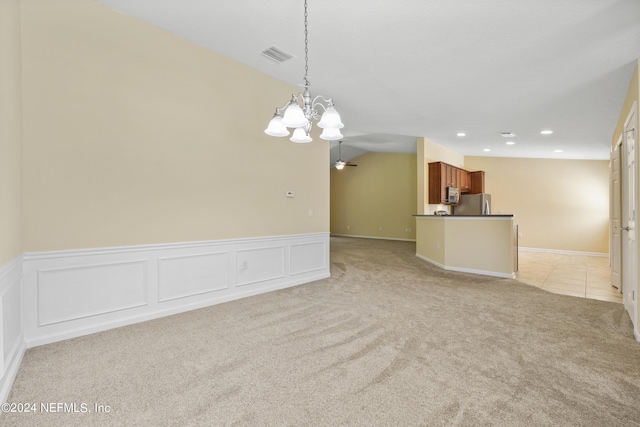 spare room featuring a chandelier, light carpet, and vaulted ceiling