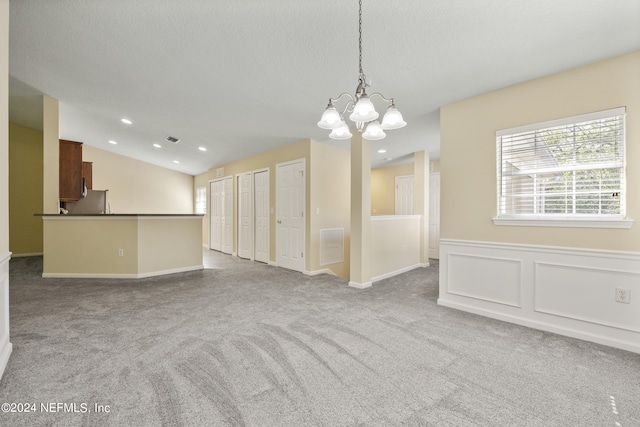 empty room with a chandelier, carpet floors, and lofted ceiling