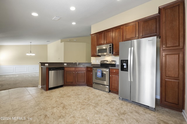 kitchen featuring kitchen peninsula, stainless steel appliances, sink, pendant lighting, and an inviting chandelier