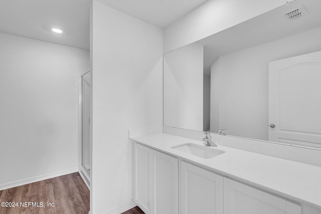 bathroom with wood-type flooring, a shower with door, and vanity with extensive cabinet space