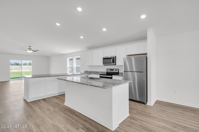 kitchen featuring appliances with stainless steel finishes, light hardwood / wood-style flooring, white cabinets, and an island with sink