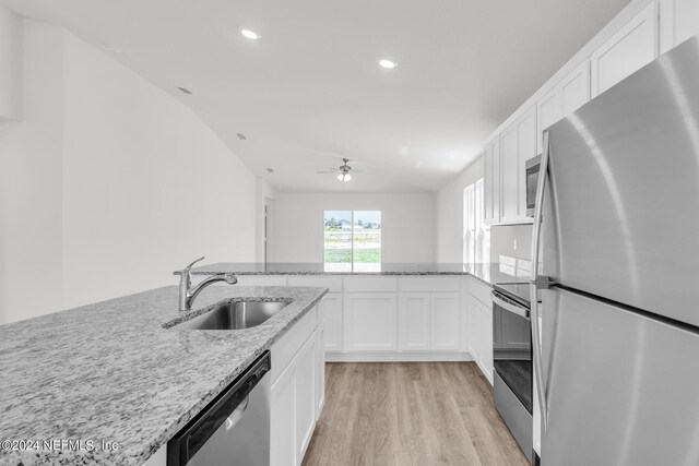 kitchen with appliances with stainless steel finishes, ceiling fan, sink, white cabinetry, and light hardwood / wood-style flooring