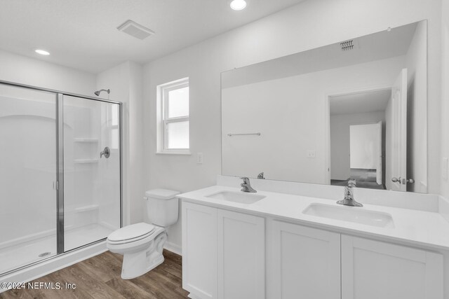 bathroom with hardwood / wood-style flooring, a shower with door, toilet, and double sink vanity