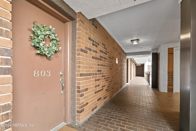 hall with a textured ceiling and brick wall