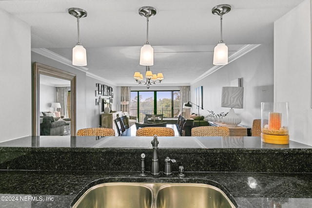 kitchen featuring decorative light fixtures, sink, dark stone countertops, and ornamental molding