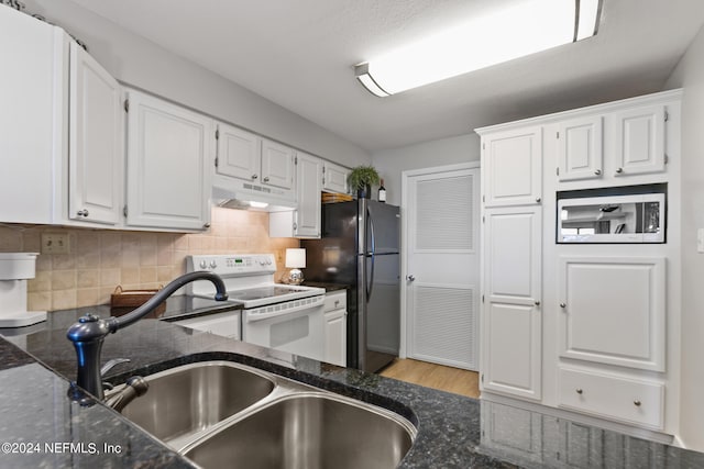 kitchen with white range with electric stovetop, dark stone counters, light hardwood / wood-style floors, tasteful backsplash, and white cabinetry