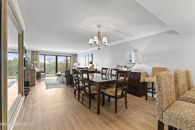 dining room with crown molding, light hardwood / wood-style flooring, a textured ceiling, and a chandelier