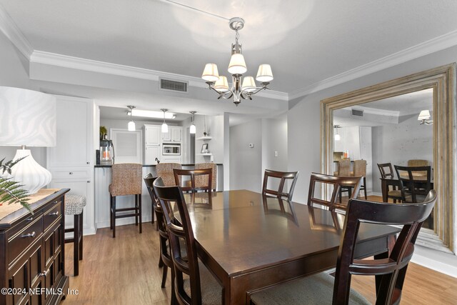 dining room featuring a chandelier, light hardwood / wood-style floors, and ornamental molding