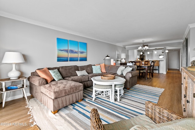 living room with a notable chandelier, ornamental molding, and hardwood / wood-style flooring