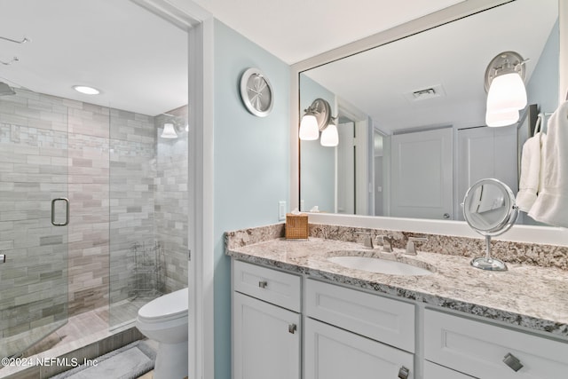 bathroom with a shower with door, oversized vanity, and toilet