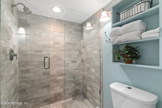 bathroom with a shower with shower door and toilet