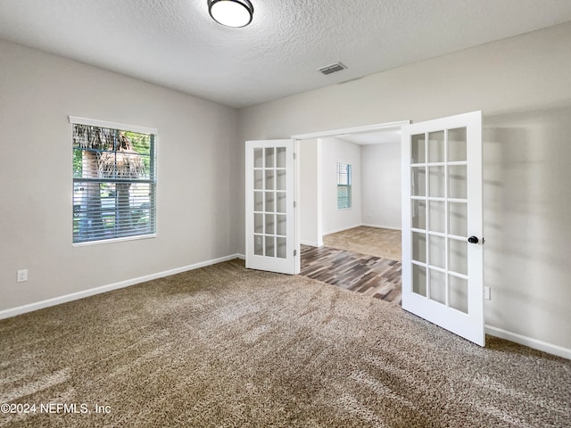 empty room with french doors, a textured ceiling, and hardwood / wood-style flooring