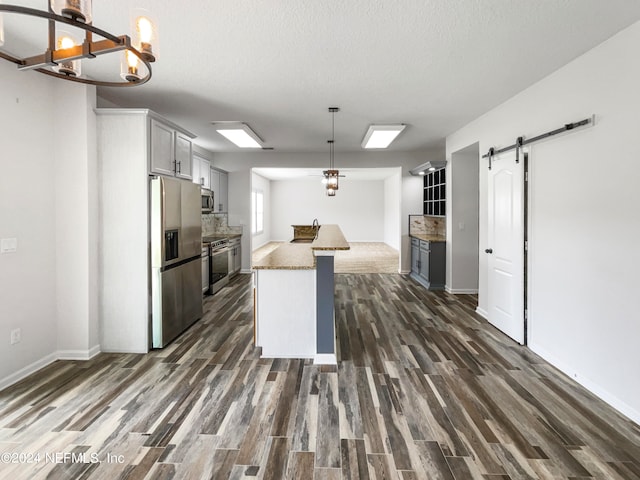 kitchen with decorative light fixtures, dark hardwood / wood-style flooring, a barn door, and stainless steel appliances