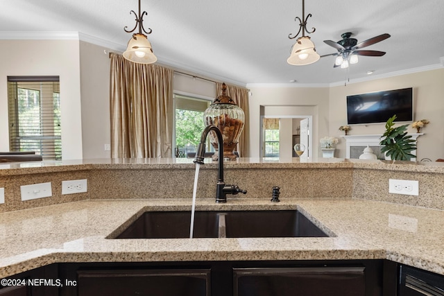 kitchen featuring sink, ornamental molding, light stone countertops, and pendant lighting