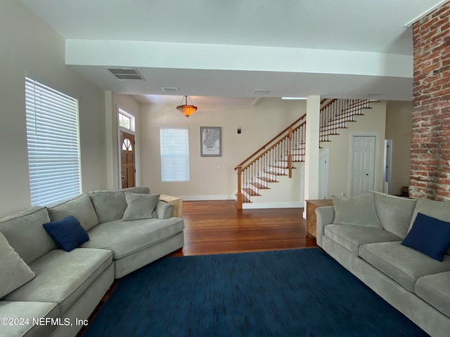 living room with brick wall and dark wood-type flooring