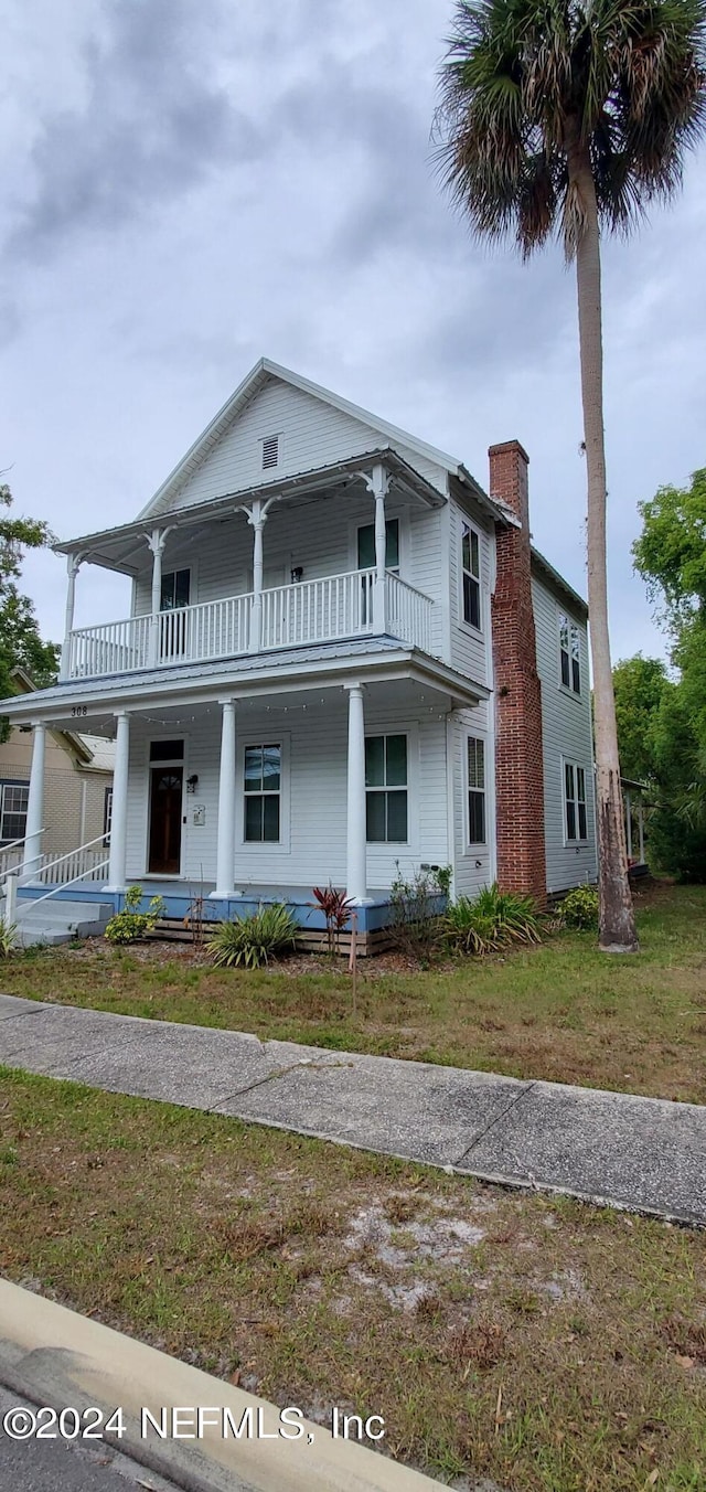 view of front of property featuring a front lawn, a balcony, and a porch