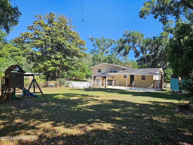 rear view of property featuring a playground, a patio area, a gazebo, and a yard