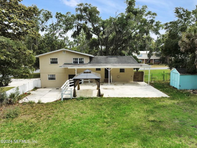 rear view of house featuring a gazebo, a storage unit, a yard, and a patio