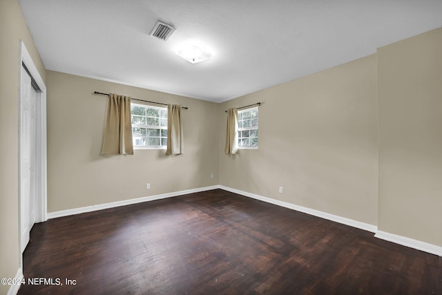 empty room featuring dark wood-type flooring and a textured ceiling