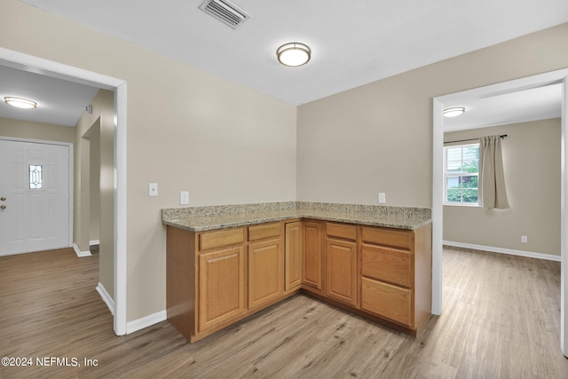 kitchen featuring light wood-type flooring and light stone counters