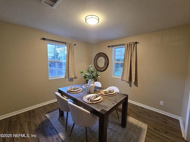 dining room with dark wood-type flooring and a textured ceiling