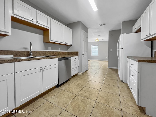 kitchen with stainless steel dishwasher, white cabinets, sink, and light tile patterned floors