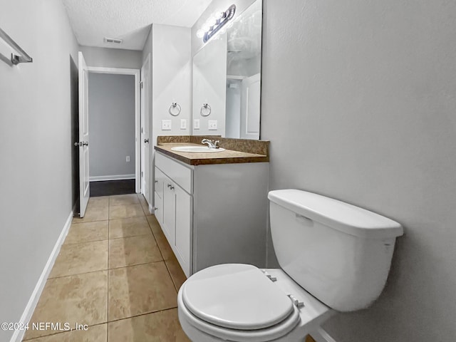 bathroom with toilet, vanity, tile patterned floors, and a textured ceiling