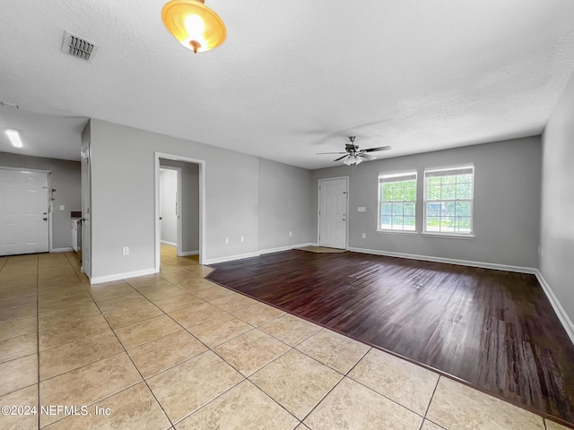 unfurnished room with ceiling fan, light tile patterned floors, and a textured ceiling