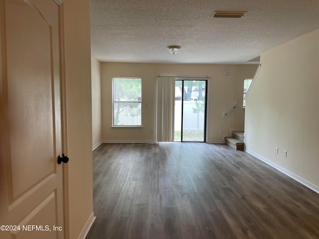 unfurnished living room featuring dark wood-style floors, stairway, and baseboards