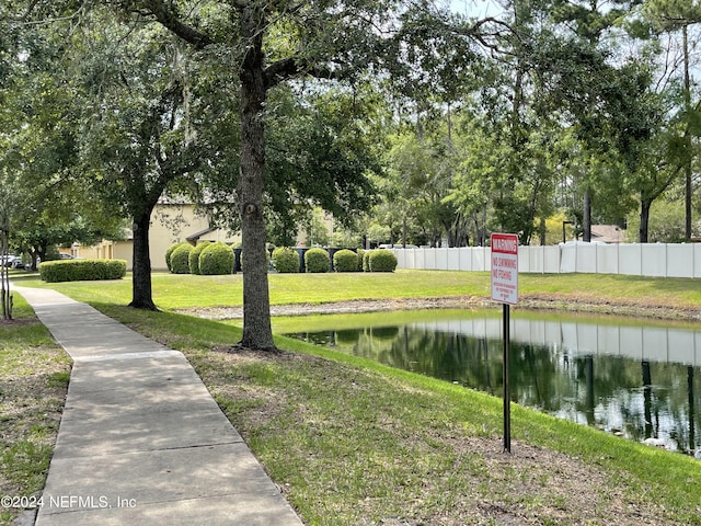 view of community with a water view, fence, and a lawn