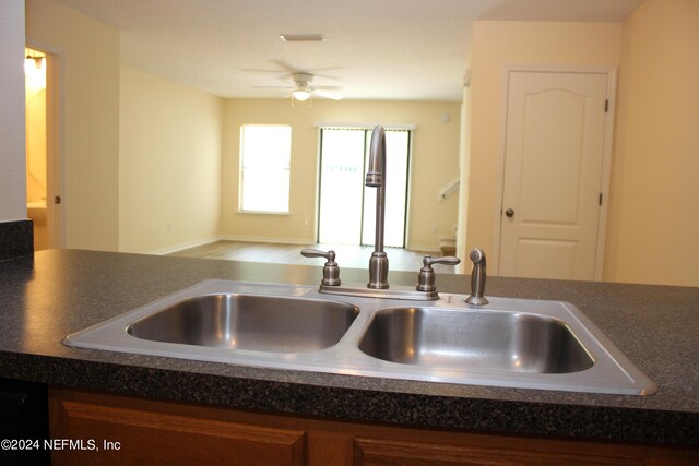 kitchen with a ceiling fan, dark countertops, a sink, and dishwasher