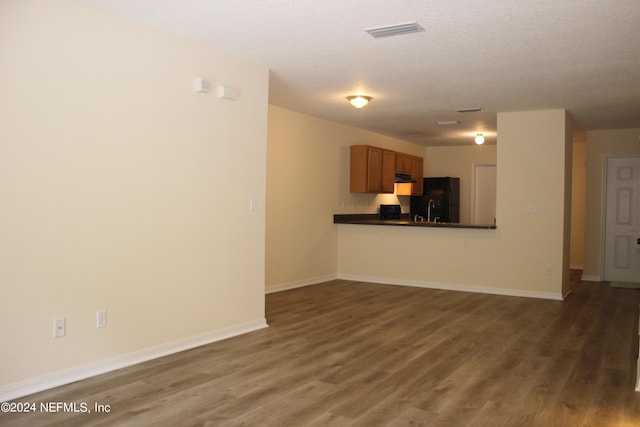 unfurnished living room with baseboards, a textured ceiling, visible vents, and wood finished floors