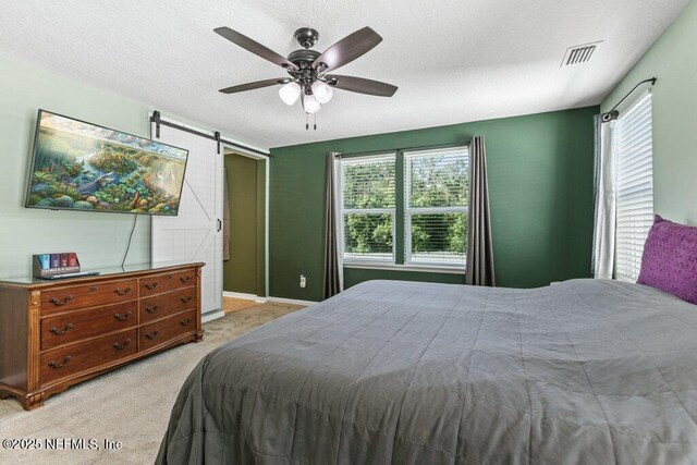 bedroom featuring light colored carpet, a barn door, multiple windows, and visible vents
