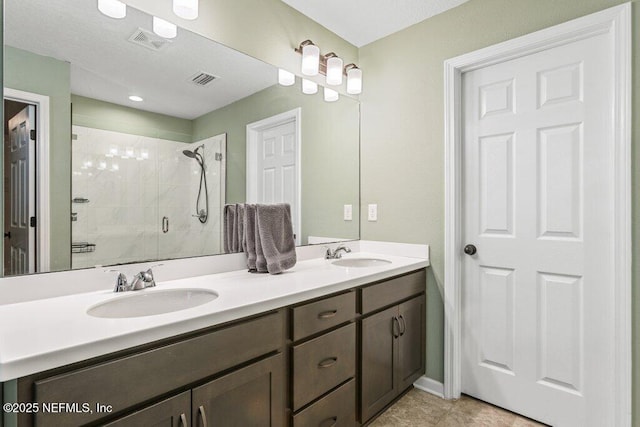 bathroom with a shower stall, a sink, visible vents, and double vanity