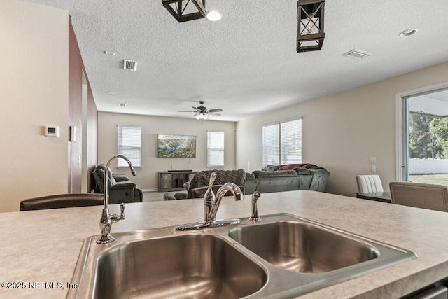 kitchen with ceiling fan, open floor plan, a sink, and light countertops
