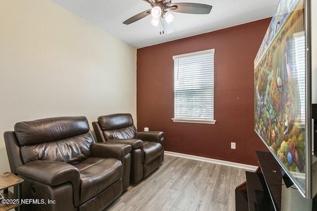 home theater room with ceiling fan, baseboards, and light wood-style floors