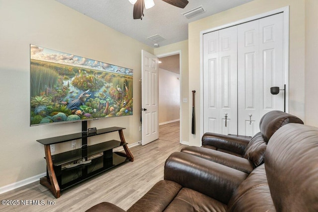 living room with light wood finished floors, baseboards, a ceiling fan, and visible vents