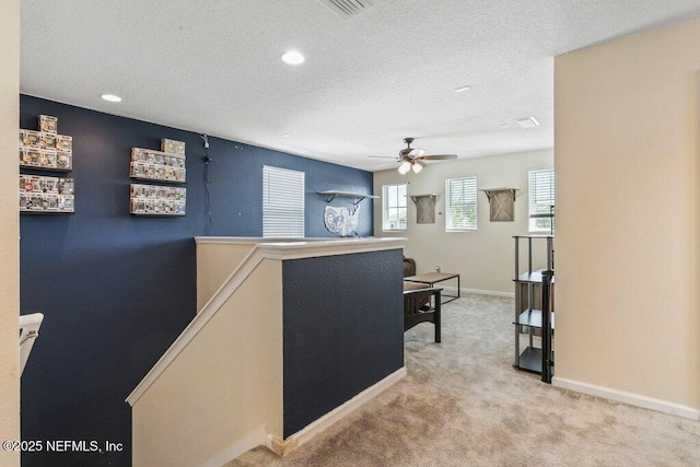 interior space featuring a ceiling fan, a textured ceiling, carpet floors, baseboards, and visible vents